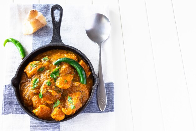 Close up traditional Indian butter chicken curry and lemon served with chapati bread on iron-cast. Top view. Copy space