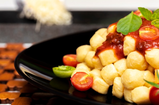 Close up on traditional italian potato gnocchi in tomato sauce with fresh basil and Cherry tomato