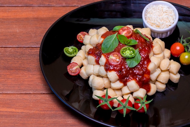 Close up on traditional italian potato gnocchi in tomato sauce with fresh basil and Cherry tomato