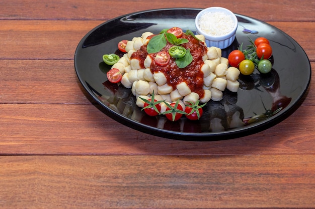 Close up on traditional italian potato gnocchi in tomato sauce with fresh basil and Cherry tomato