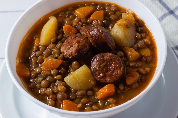 Крупный план традиционного чечевичного супа с ножками, морковью и чоризо. Средиземноморская кухня