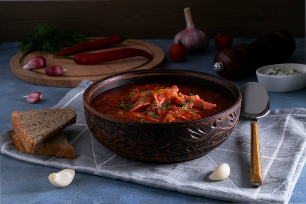 Close-up of the traditional russian soup borscht made from\
cabbage, beets and other vegetables served in a clay ceramic plate\
with sour cream and garlic. national cuisine concept. selective\
focus.