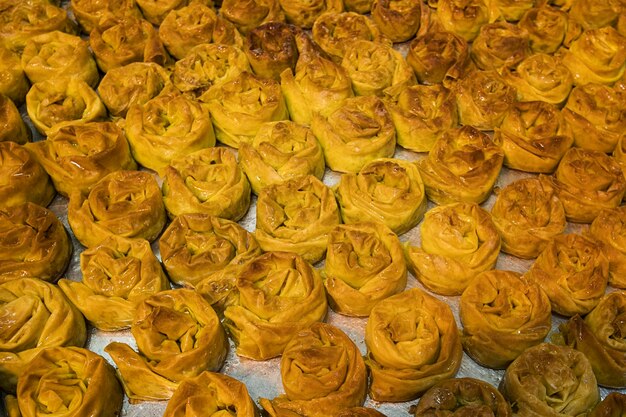 Close up of a tray with freshly baked sweet buns. Delicious and appetizing sugary treats set on bakery sheet. Confectionary store selling brownish pastry. Buying and eating sweetened buns.