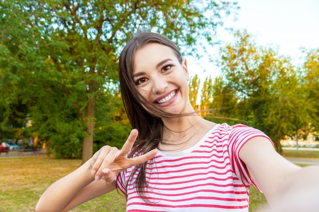 トレンディな女の子の顔のクローズアップはselfie写真を作っています。