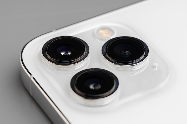 灰色の表面に現代のスマートフォンのトリプルレンズカメラのクローズアップ