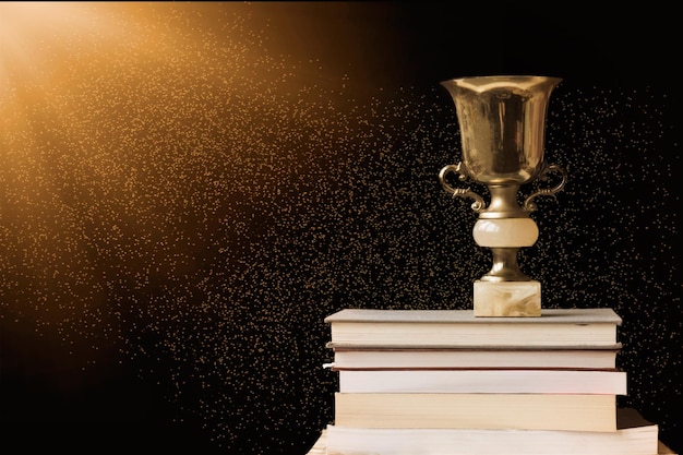 Photo close-up of trophy on stacked books against black background
