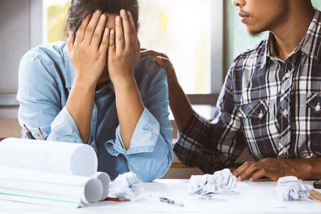 Close-up of troubled female crying and covering face with man to console her