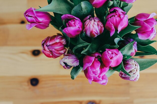 Close up tulips bouquet in a vase over wooden background 8 march greeting