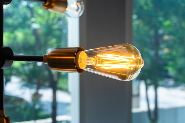 Close up to tungsten lamp light that is hung on the steel stock of ceiling on blur background