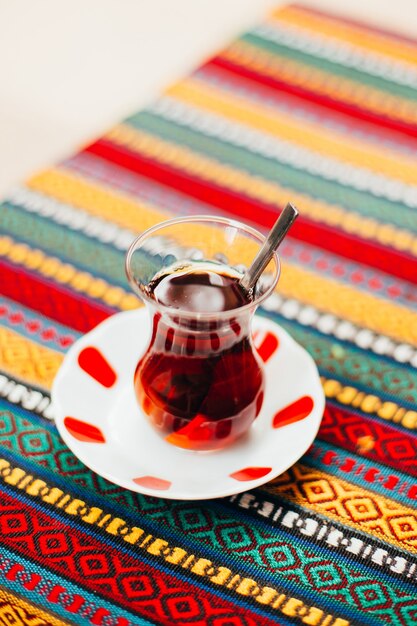 Close-up of turkish tea in a transparent glass on a table with a colorful tablecloth