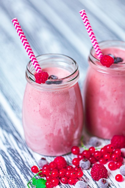 Close-up twee potten yoghurt smoothie met cranberry frambozen bosbes op houten tafel