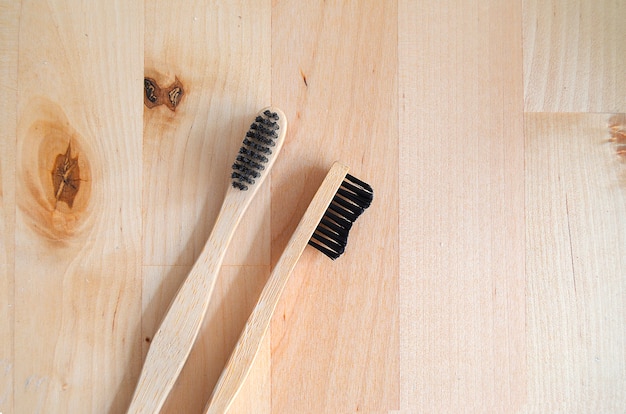 Close up of two bamboo toothbrushes on wood table