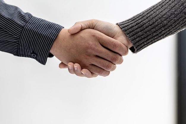 Close-up two business men holding hands, Two businessmen are agreeing on business together and shaking hands after a successful negotiation. Handshaking is a Western greeting or congratulation.