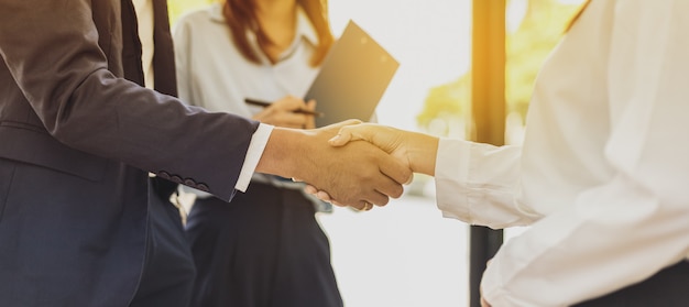 Close-up two business men holding hands, Two businessmen are agreeing on business together and shaking hands after a successful negotiation. Handshaking is a Western greeting or congratulation.