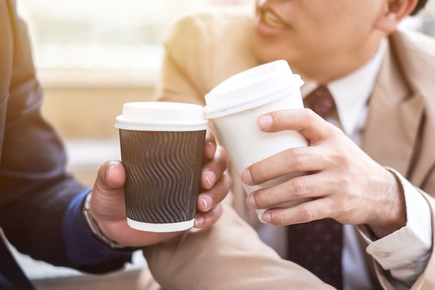 Close-up of two business partners holding cups of coffee