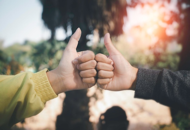 Close up two children holding hand together over grass with sun lightAfter work something success