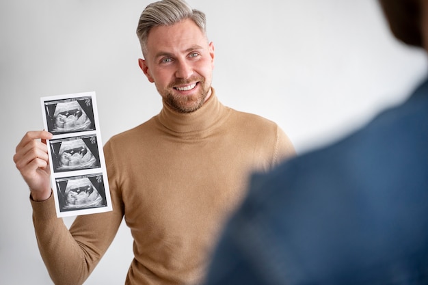 Foto primo piano su due papà che guardano gli ultrasuoni del bambino