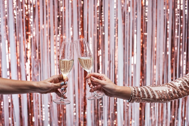 Close-up of two female hands clinking champagne glasses.