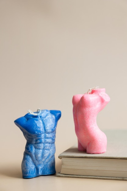 Close up of two handmade candles from soy wax in shape man torso and woman body isolated on pastel background