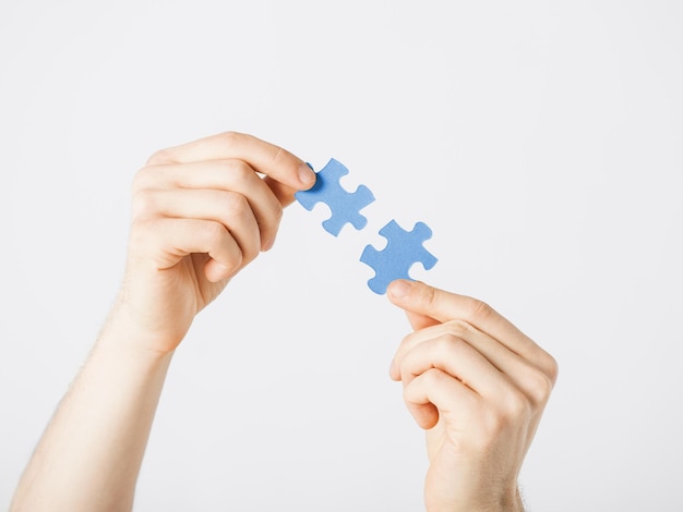 close up of two hands trying to connect puzzle pieces