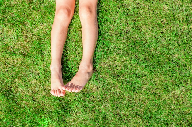 Photo close-up of two legs of a young girl on the grass on the lawn