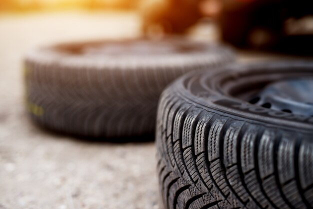 Close up of two new tires laying on the pavement beside each other in a car workshop.