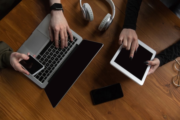 Photo close up of two people, couple using smartphone, laptop, smartwatch, education and business concept, communication during self-insulation. surfing, online shopping, working, studying, chatting.