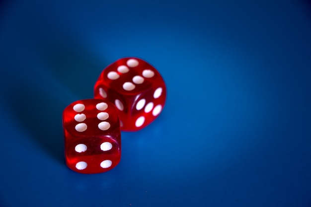 Photo close-up of two red dices with sixes on the top on a blue background