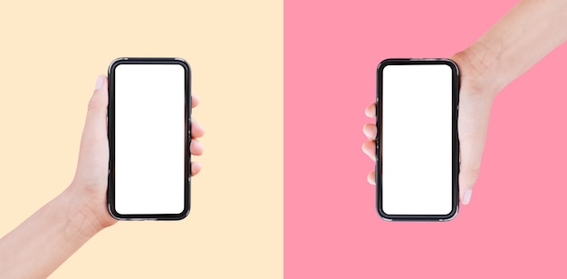 Close-up of two smartphones in hands on surfaces of pastel yellow and pink of colors.