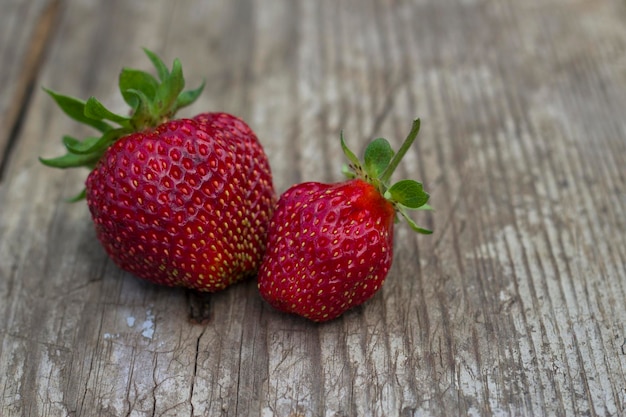 A close up of two strawberries on a wooden table