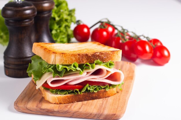 Primo piano di due panini tostati con prosciutto fresco, formaggio e verdure sullo sfondo.