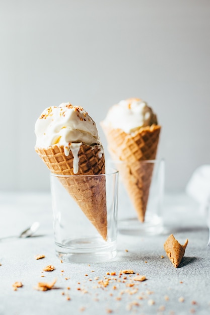 Close-up of two white ice creams in waffle cups on gray background