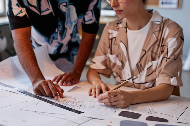 Close up of two young architects working on interior design project in office with dim lighting copy