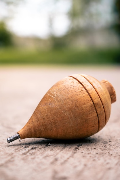 Photo close up of a typical wooden spinning top laying on concrete.