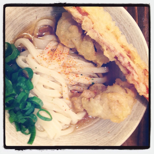 Foto close-up di spaghetti udon con tempura serviti sul piatto