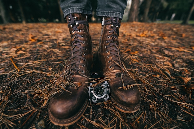 close-up uitzicht op mannelijke benen in vintage lederen laarzen en horloges in herfst park
