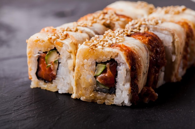 Close-up of unagi sushi roll set on a black slate background