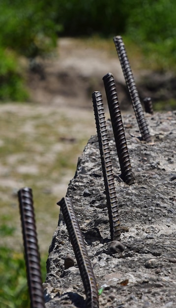 Photo close-up of uneven metal rods in concrete wall