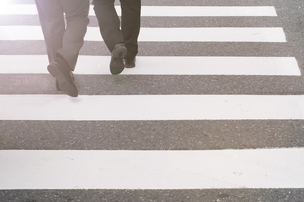 Primo piano su gambe di persone non identificate che attraversano la strada