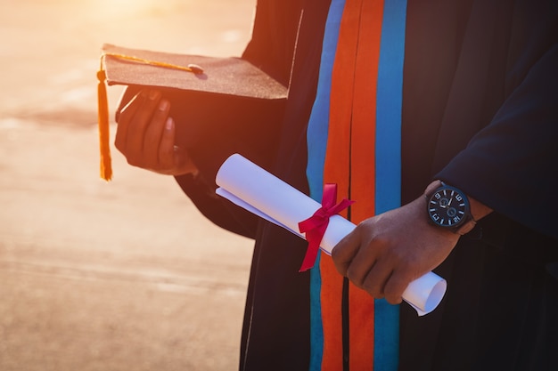 Photo close up of a university graduate holding degree certificate and mortarboard