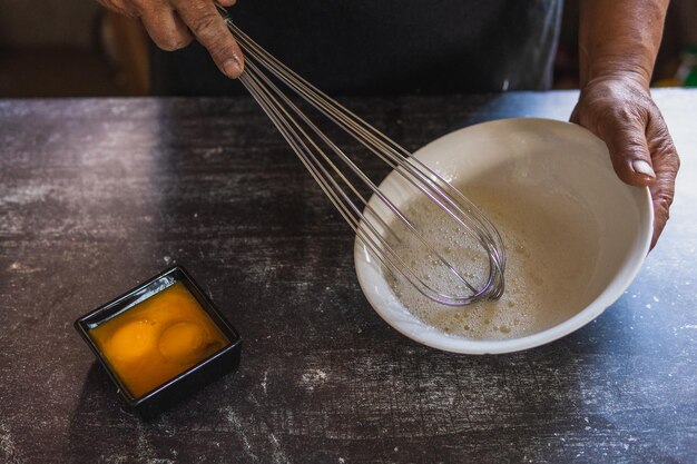 close up of unrecognisable adult male baker beating eggs with hand mixer