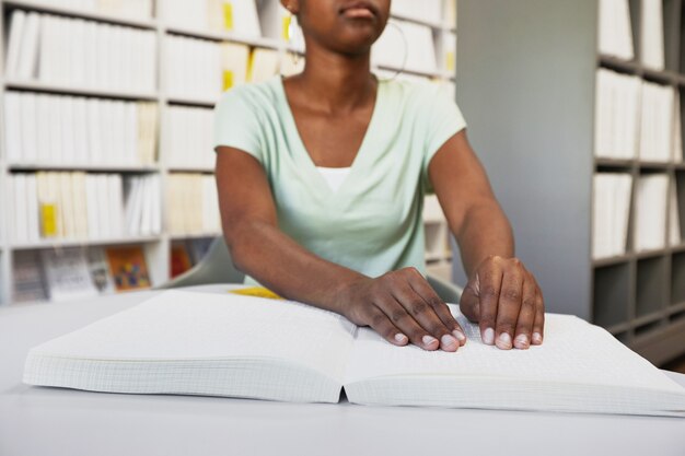 Close up of unrecognizable africanamerican woman reading braille book in college library copy space