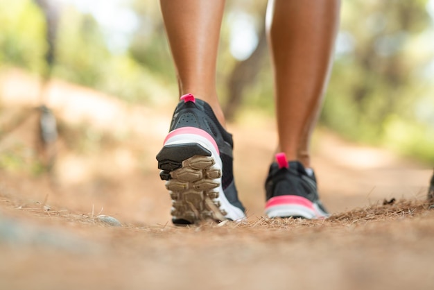 Close-up of an unrecognizable female person walking through the pine forest during outdoor training. Rear view.