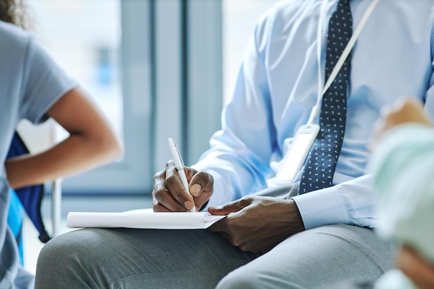 Photo close up of unrecognizable male therapist taking notes during session with support group copy space