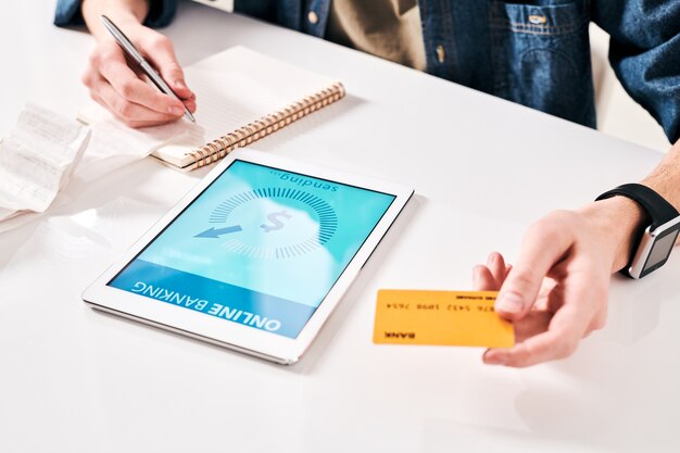 Close-up of unrecognizable man checking receipt and using online bank app to pay bill for purchase