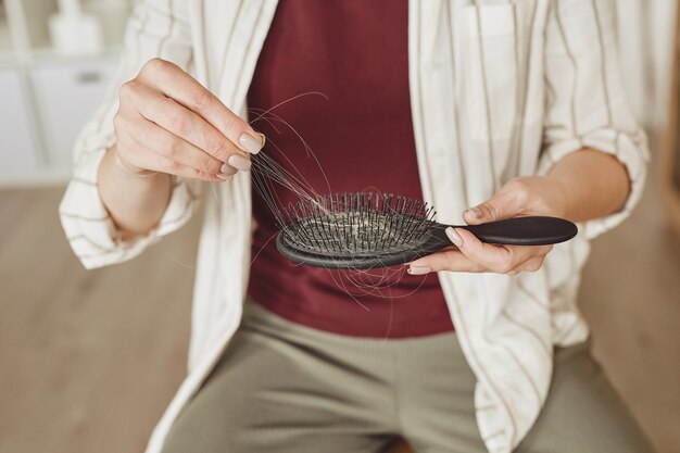 Close up irriconoscibile donna tenendo la spazzola piena di capelli, perdita di capelli e concetto di alopecia, copia dello spazio