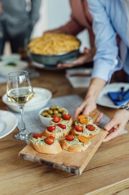 Primo piano della donna irriconoscibile che serve antipasto al tavolo da pranzo.