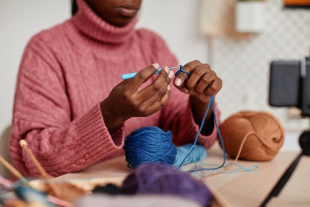 Close up of unrecognizable young africanamerican woman knitting at home copy space