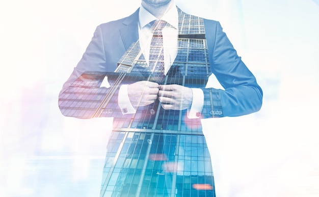 Close up of an unrecognizable young businessman buttoning his suit standing against a modern cityscape. Toned image double exposure