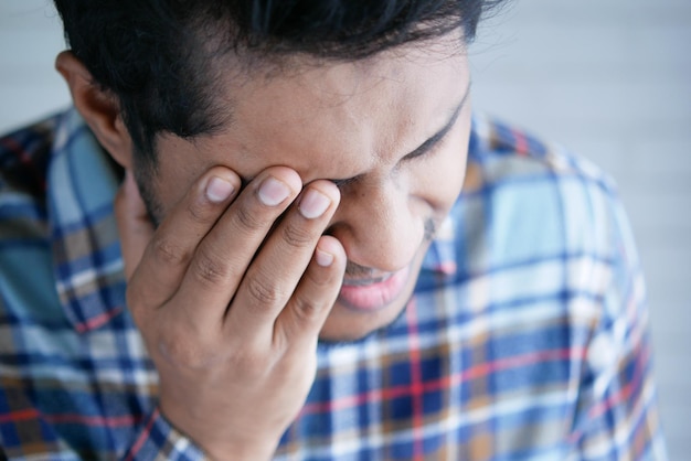 close up of upset man suffering from strong eye pain